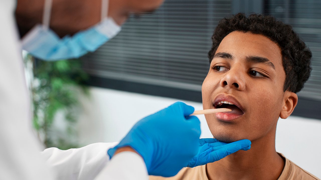 Jovem sendo atendido pelo médico que avalia sintomas de doenças na boca.