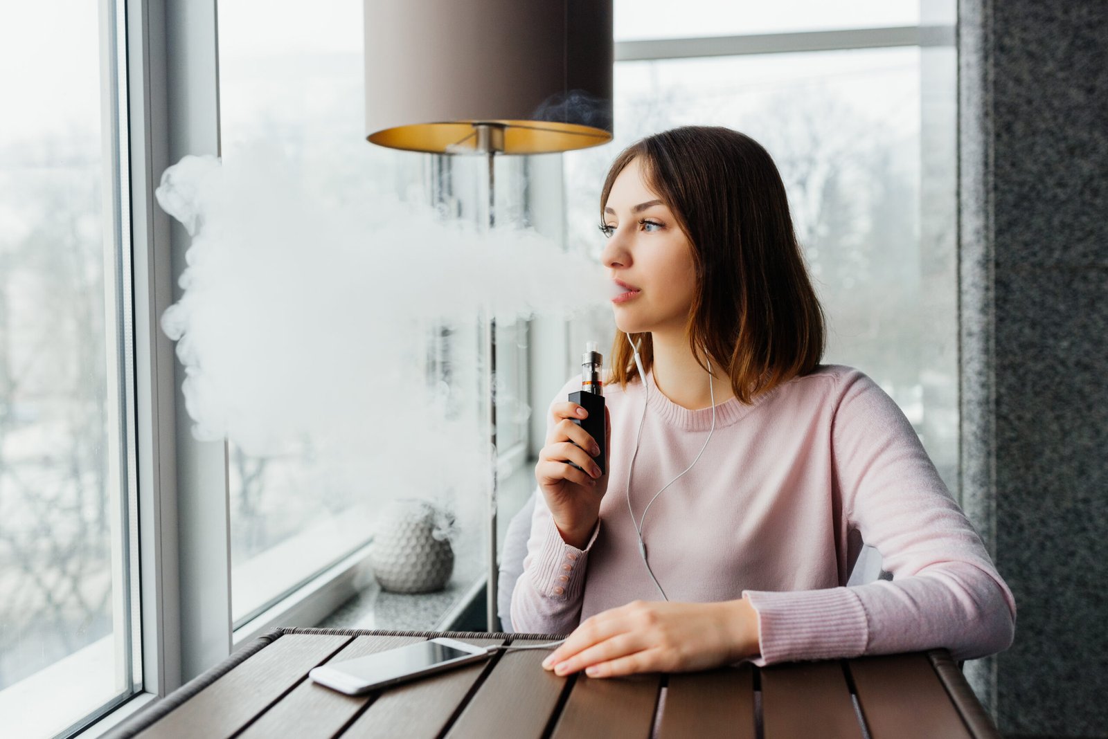 Menina moderna fumando um vape ou pod e acendendo um alerta para os riscos de cigarros eletrônicos para os dentes.