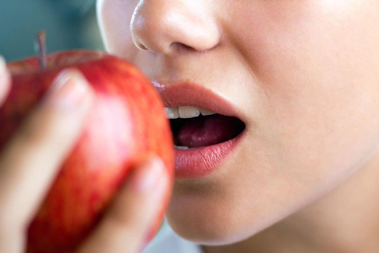 Mulher mordendo uma maça enquanto lê uma lista do CROOL Centro Odontológico sobre alimentos bons para a saúde bucal