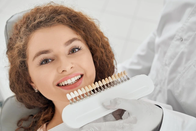 Mulher na cadeira do dentista experimentando facetas de porcelana.
