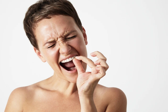 Mulher segurando um dente que caiu.