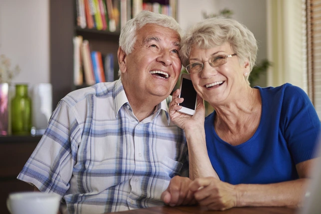 Um casal de idosos sorrindo feliz e mostrando a durabilidade do implante dentário.