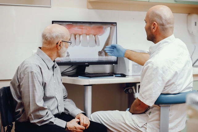 Homem velho olhando para um implante dentário no computador.