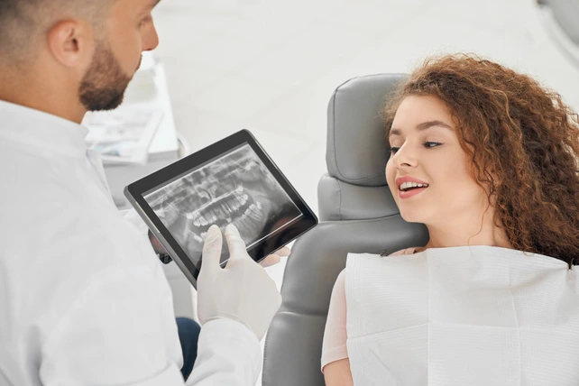 Mulher jovem na cadeira do dentista vendo um raio-x da boca.