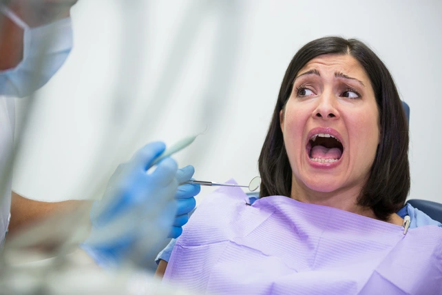 Mulher assustada na cadeira do dentista.
