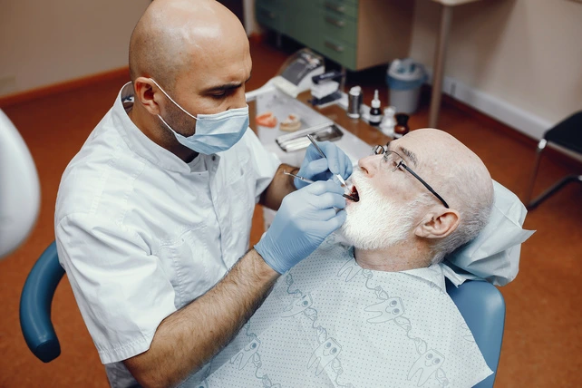 Dentista fazendo implante dentário em um senhor de idade.